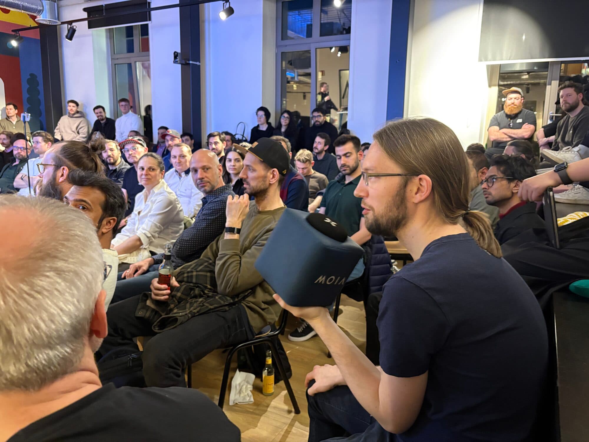 Attendees listening closely, one holding a headset, during a talk at an AI BEAVERS event