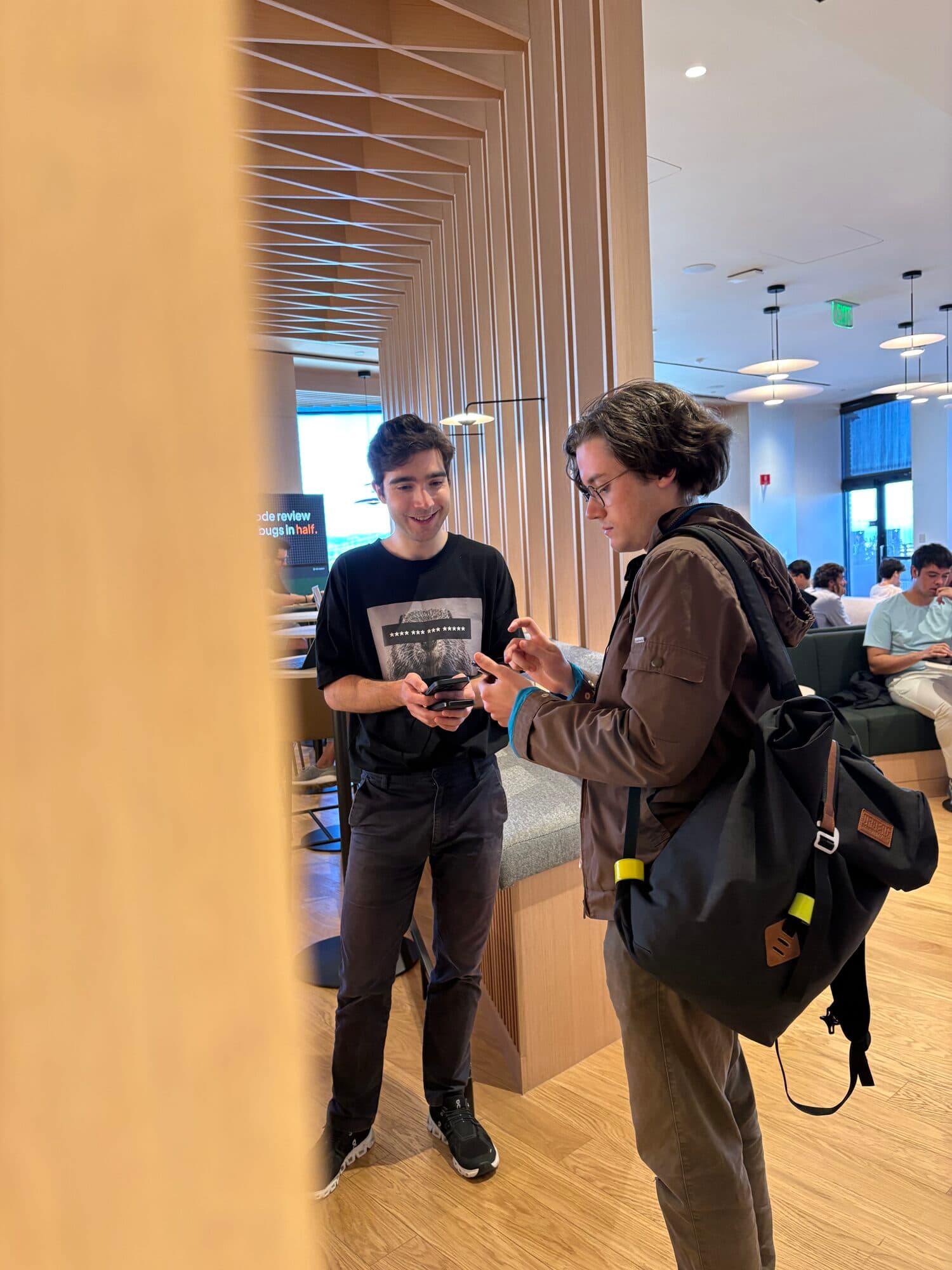 Two attendees talking in a hallway at an AI BEAVERS event, one with a backpack on