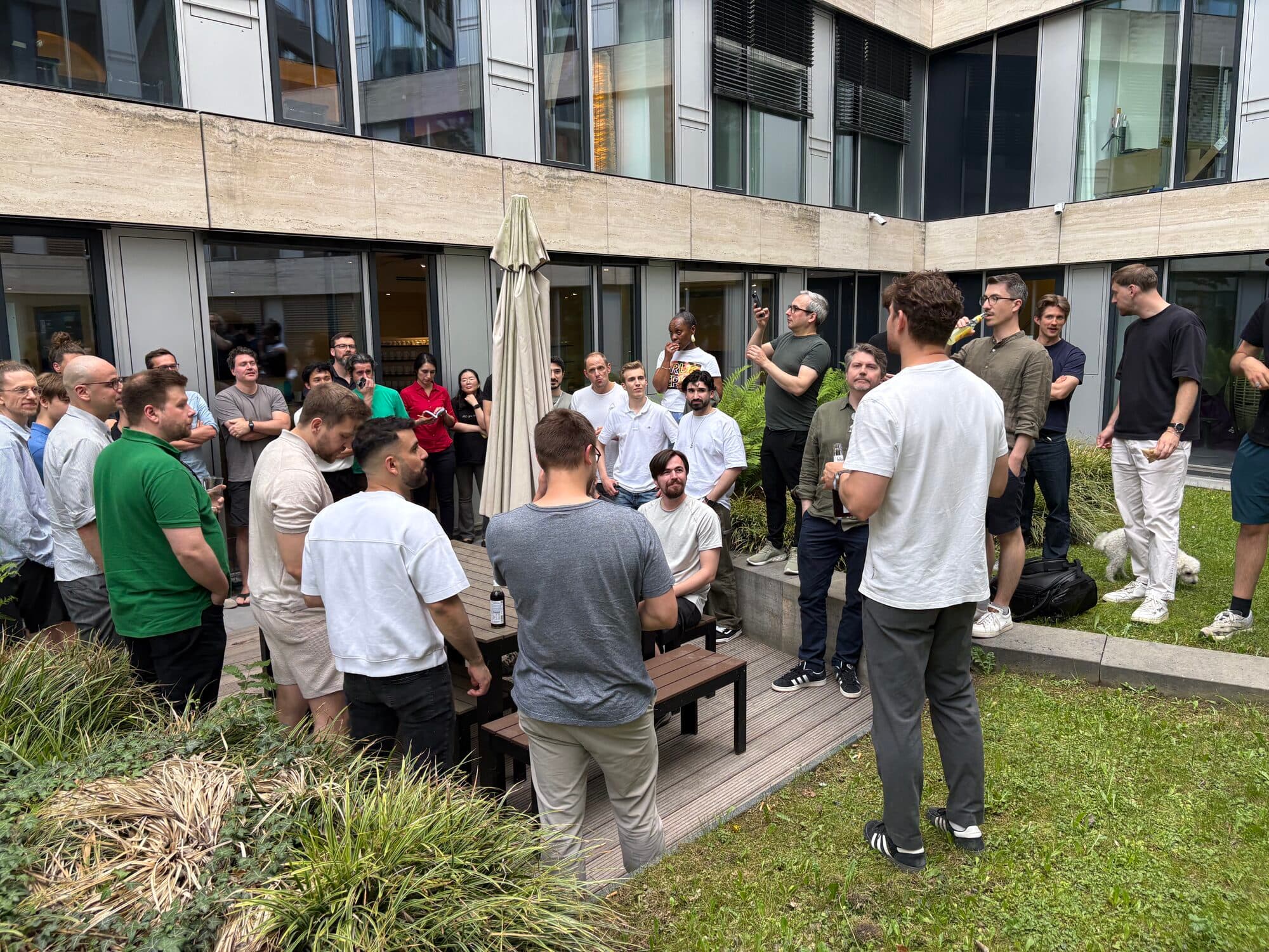 A large group of attendees chatting on a lawn in front of an office building at an AI BEAVERS event