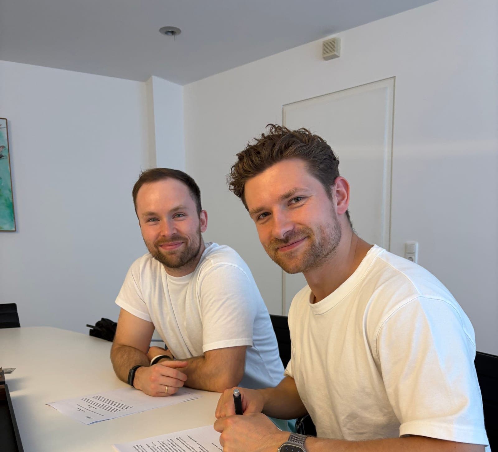 AI BEAVERS co-founders Alex, left, and Vlady smiling at a meeting table as they sign papers