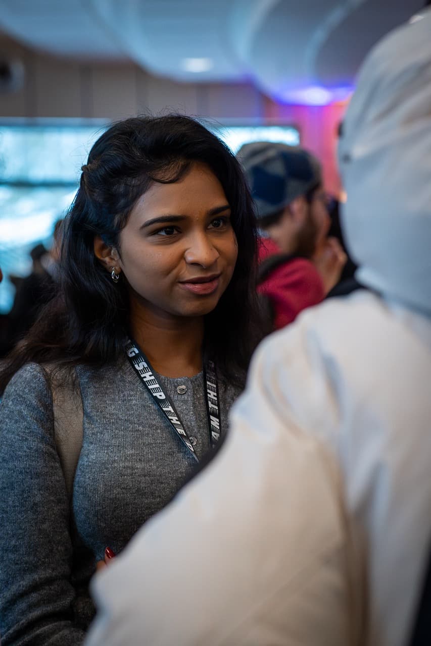 An attendee with a lanyard smiling during a conversation at the AI BEAVERS January 2026 hackathon in Hamburg