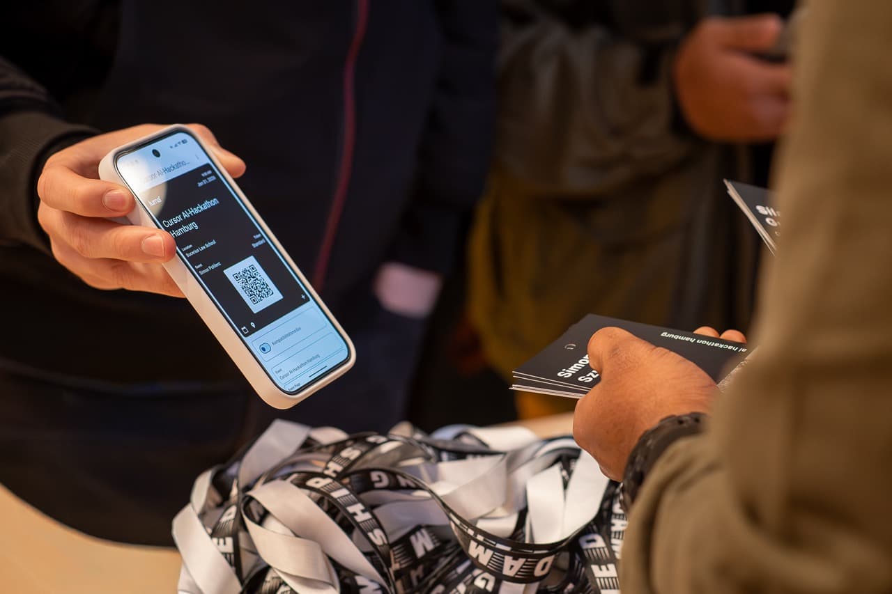 An attendee showing a phone ticket at check-in while lanyards wait on the table, at the AI BEAVERS January 2026 hackathon