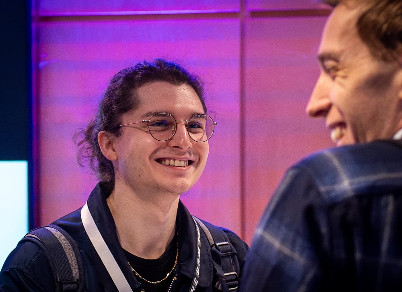 An attendee in glasses smiling under pink light at the entrance of the AI BEAVERS January 2026 hackathon in Hamburg