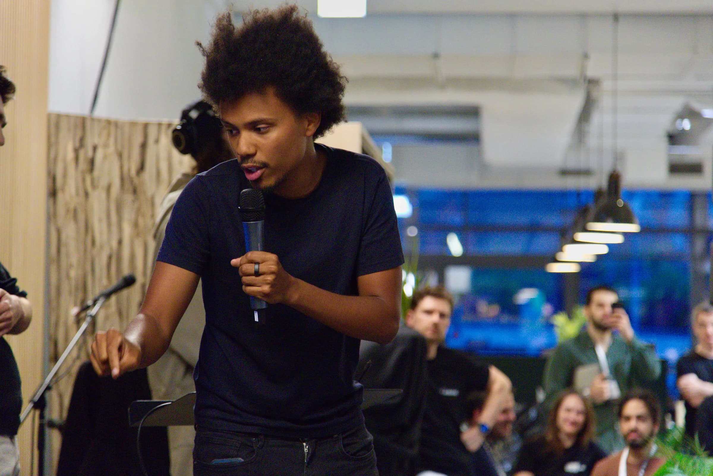 A finalist speaking into a microphone in front of the audience at the AI BEAVERS Founder Hackathon in Hamburg