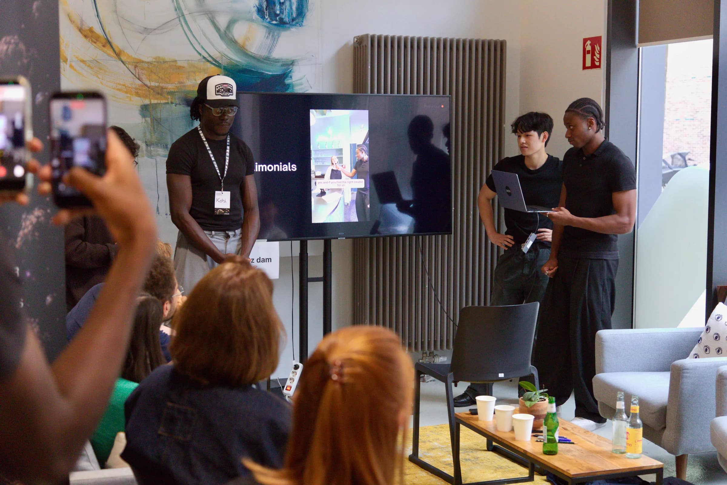Attendees filming a team pitching beside a screen at the AI BEAVERS Founder Hackathon in Hamburg