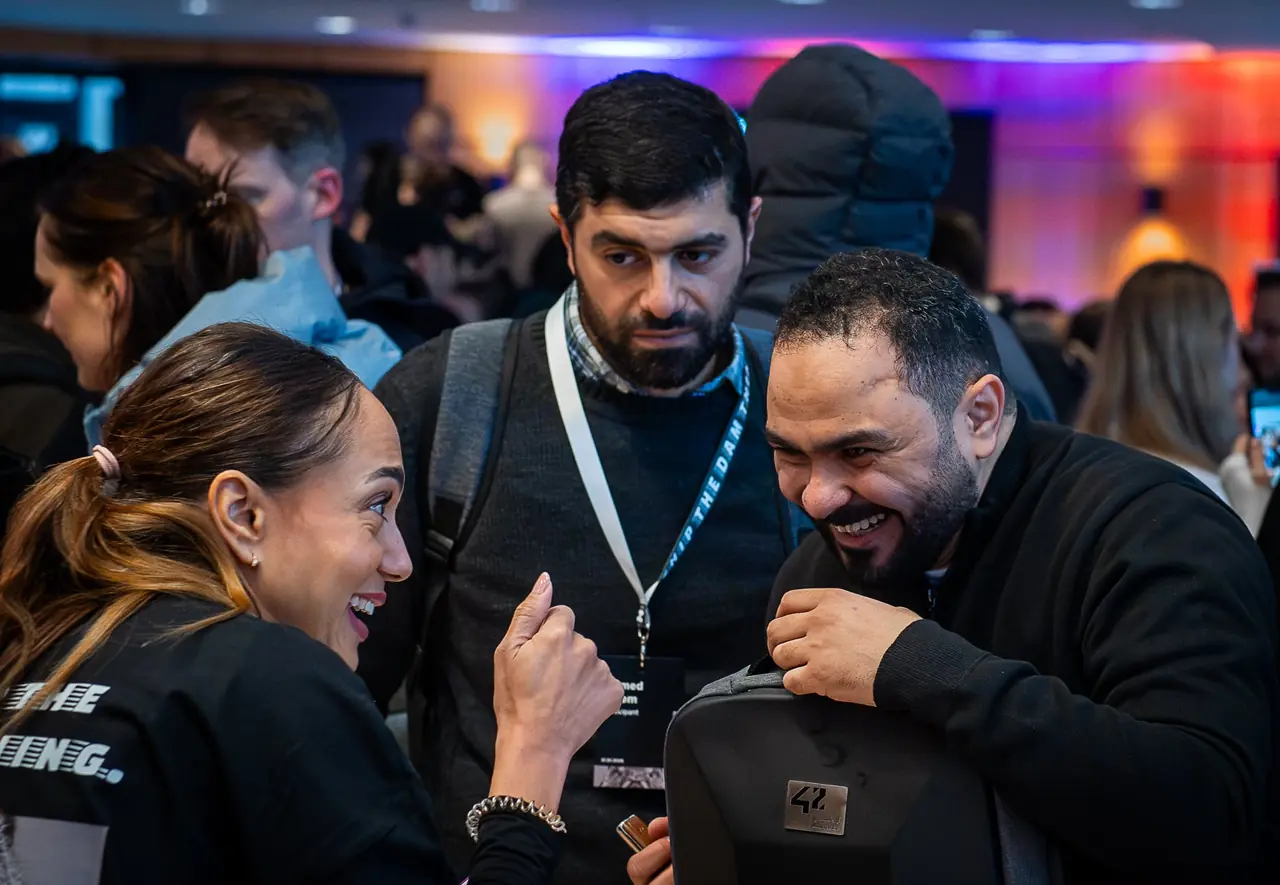 AI BEAVERS members with lanyards laughing together in the crowd at a Hamburg hackathon